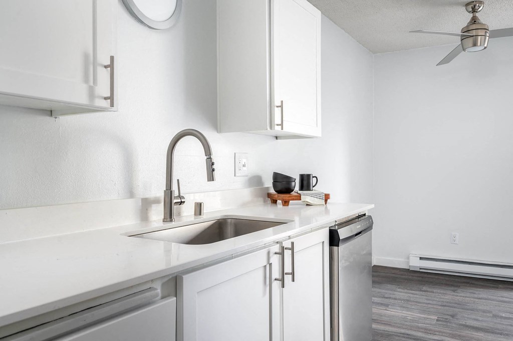 a white kitchen with white cabinets and a stainless steel sink